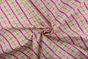 This quilting print features a diagonal plaid design in purple, pink, lime green, and a hot pink against a white background.