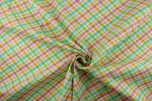  This quilting print features a diagonal plaid design in yellow, pink, green, and a pale teal blue against a white background.