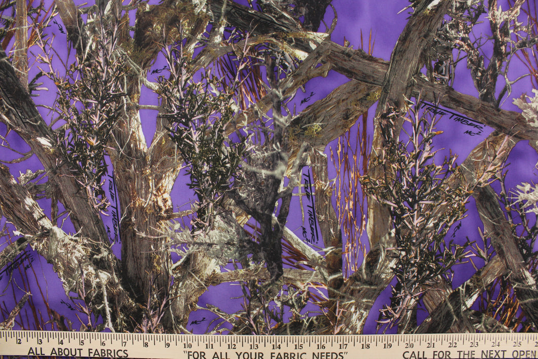 This camo fabric features realistic branches and leaves in varying shades of brown, gray, white and black against a purple background. 
