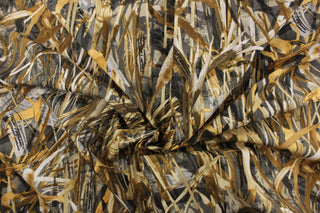 This camo fabric features realistic water grass in brown, tan, white and black against a dark gray background. 
