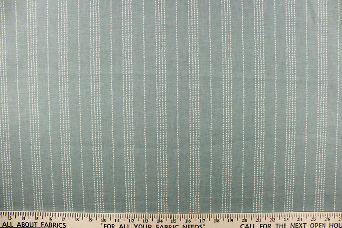  This fabric features a multiple white dot stripes against a mist green background.