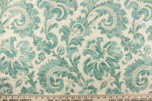 This beautiful fabric features a whimsical floral design in teal green with a beige outline against a creamy white background. 