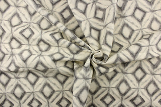 This fabric features a geometric design of diamonds in varying shades of gray against a off white. 