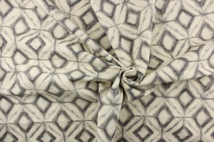 This fabric features a geometric design of diamonds in varying shades of gray against a off white. 