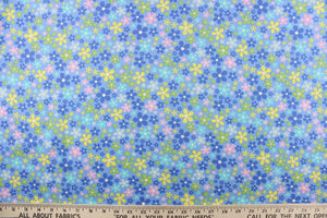This cute cotton fabric features a floral design in varying shades of blue, with yellow, pink, green, and white against a blue background, 