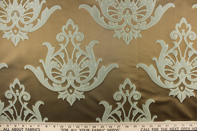This lightweight Jacquard fabric features a woven damask design on a silken background. The colors included are brown/taupe and teal.