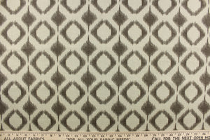 This fabric features a geometric design in diamond shapes in a brown tone against a gray brown background. 