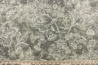 This fabric features a whimsical floral design in a off white against a gray with green undertones.