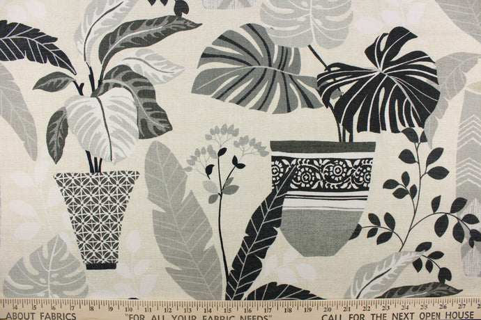 This fabric features a floral design of flowers in pots in varying shades of gray, black, and white against an off white or natural background.