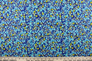 This quilting print features a beautiful floral design in varying shades of blue, yellow and white against a royal blue background