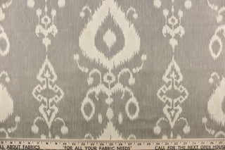  This fabric features an ikat design in a off white against a gray.