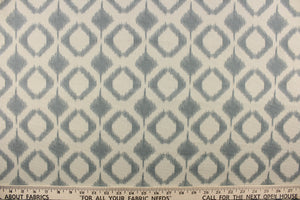 This fabric features a geometric design in diamond shapes in a blue gray tone against a off white background. 