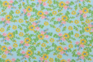 This soft quilting print features a beautiful floral design in pink, yellow, green and blue against a light blue background.