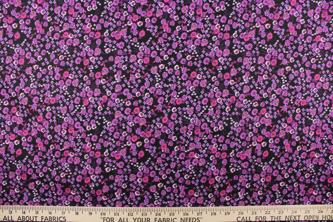  This quilting print features a beautiful floral design in varying shades of purple, with hints of white and a deep pink against a black background.
