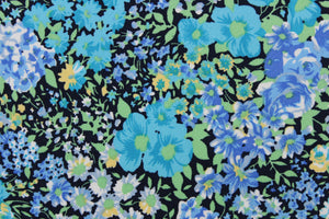 This quilting print features a floral design in varying shades of blue, teal, and yellow, green with hints of white against a black background. 