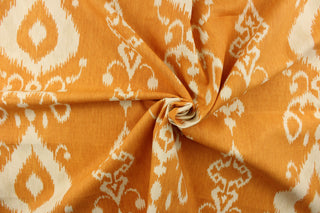 This fabric features an ikat design in a  yellow orange and off white. 