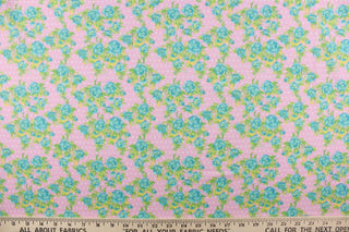  This quilting print features a beautiful rose design in turquoise blue and green with hints of yellow against a pink background with white dots. 