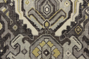 This fabric features an Aztec design in mute gold, shades of gray, and off white with hints of black. 