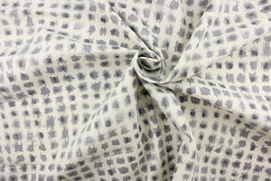 This screen printed fabric features ink blot shapes in shades of gray on a off white background.