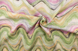 This screen printed fabric features abstract waves in shades of green, yellow, pink, purple, white and brown with metallic silver accents. 