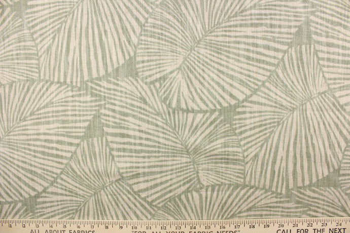 This pattern features large tropical leaves in sage green on a natural linen background