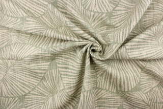 This pattern features large tropical leaves in sage green on a natural linen background