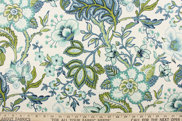  This printed decorative fabric features a beautiful floral design and foliage in shades of blue, teal and green on a white background.