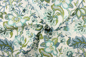  This printed decorative fabric features a beautiful floral design and foliage in shades of blue, teal and green on a white background.