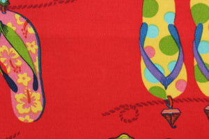 This outdoor fabric features brightly colored flipflops in yellow, pink, green, blue, and turquoise against red background. 