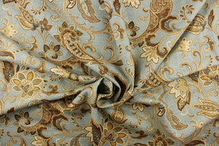 This linen rayon blend fabric features a paisley design in brown, khaki, blue, cream and hints of gold against a light blue gray background.