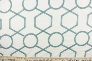 This fabric features a modern geometric design artfully embroidered in sky blue on a white background.  