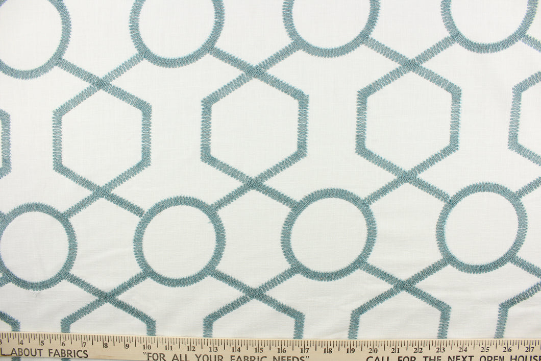 This fabric features a modern geometric design artfully embroidered in sky blue on a white background.  
