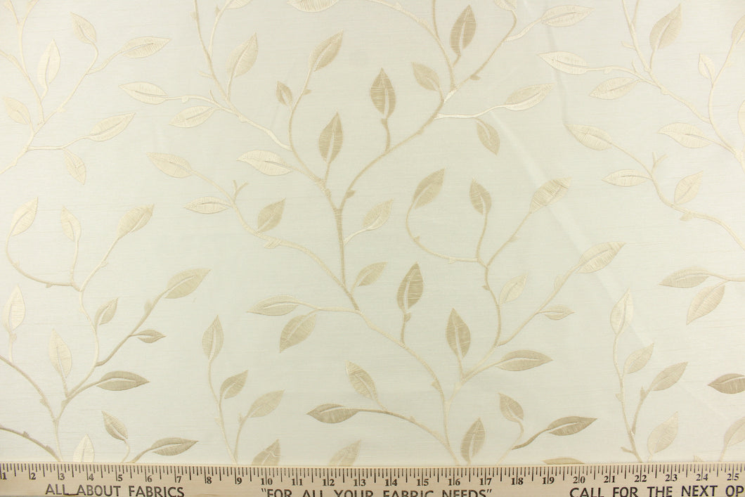 This luxurious duotone fabric features embroidered foliage on a silky cream background.