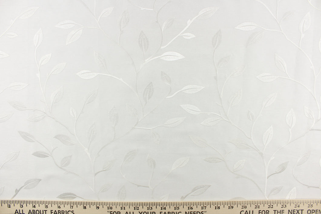  This luxurious duotone fabric features embroidered leaves on a silky white background.