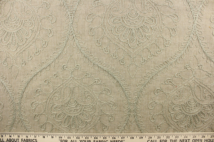 This fabric features an embossed medallion design in light green on a dark beige background.  