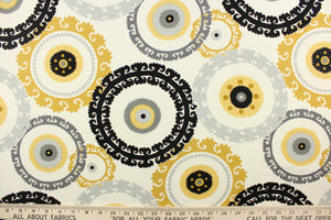  This fabric features a multi decorative circle design in gold, gray, and black against a white background 