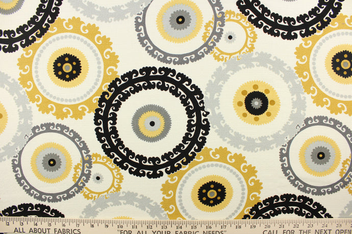  This fabric features a multi decorative circle design in gold, gray, and black against a white background 