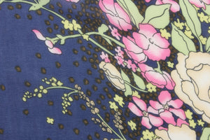 This chiffon fabric features a floral design in pink, white, green, brown, cream, pale yellow against a dark blue background. This floral design goes along the left and right side of the fabric. This fabric is sheer. 