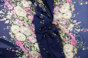 This chiffon fabric features a floral design in pink, white, green, brown, cream, pale yellow against a dark blue background. This floral design goes along the left and right side of the fabric. This fabric is sheer. 