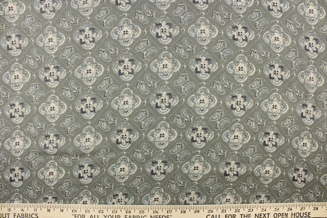 This chiffon fabric features a medallion design in blue, gray, and navy against a grayish green. This fabric is sheer.