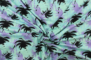This jersey fabric features a palm tree design in black, purple, pale blue and seafoam green.