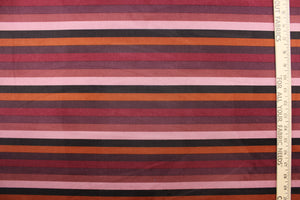 This suede lycra fabric features a horizontal stripe design in orange, black, purple, plum, mauve, and pale purple. 