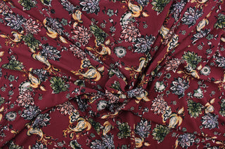 This georgette fabric features a floral design in green, golden yellow, white, black, and pale purple against a maroon background. 