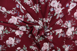 This georgette fabric features a floral design in pink, blue, and green against a burgundy background. 
