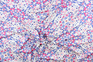 This lycra jersey blend fabric features a floral design in blue, pink, white, and orange.