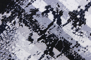 This 8 way lycra blend fabric features a snake design in a diamond in gray, black, and white.