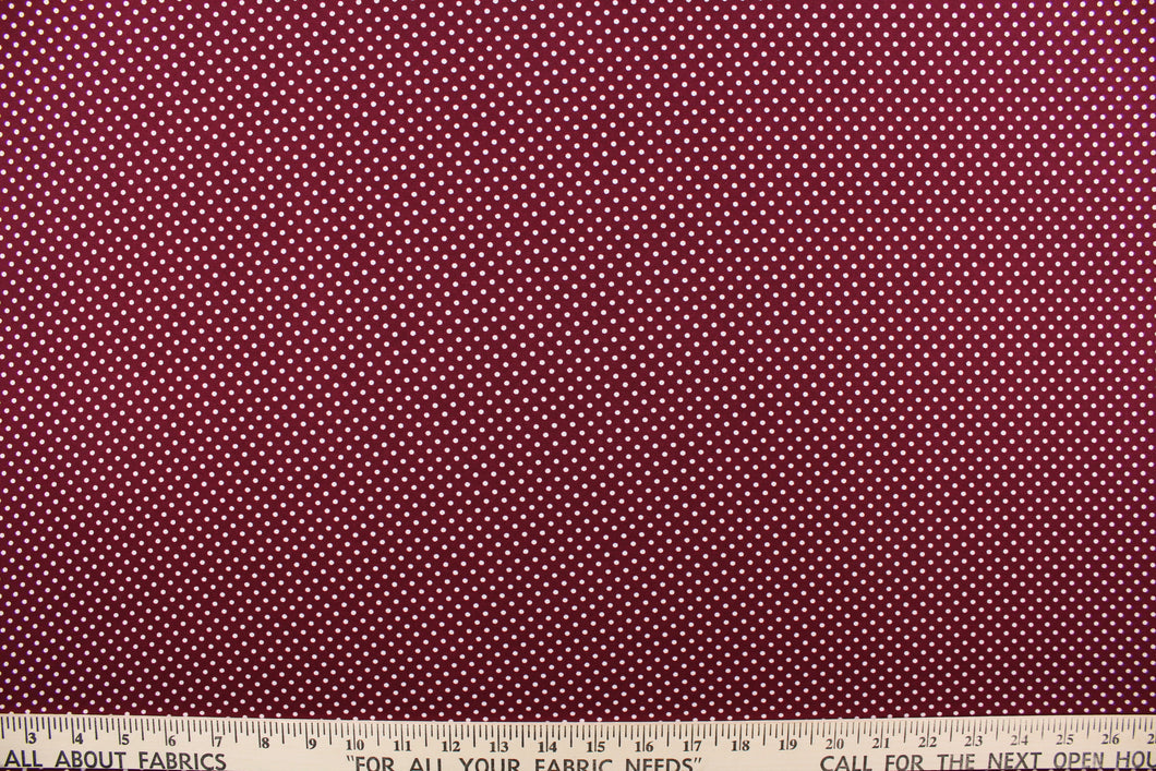 This interlock jersey fabric features a dot design in white against a burgundy background