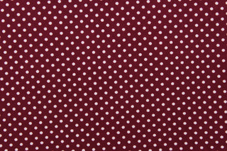 This interlock jersey fabric features a dot design in white against a burgundy background
