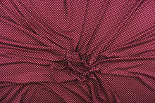 Load image into Gallery viewer, This interlock jersey fabric features a dot design in white against a burgundy background
