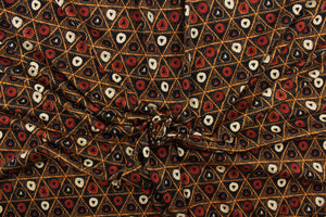 This jersey fabric features a tribal geometric design in orange, cream, black, and dark orange